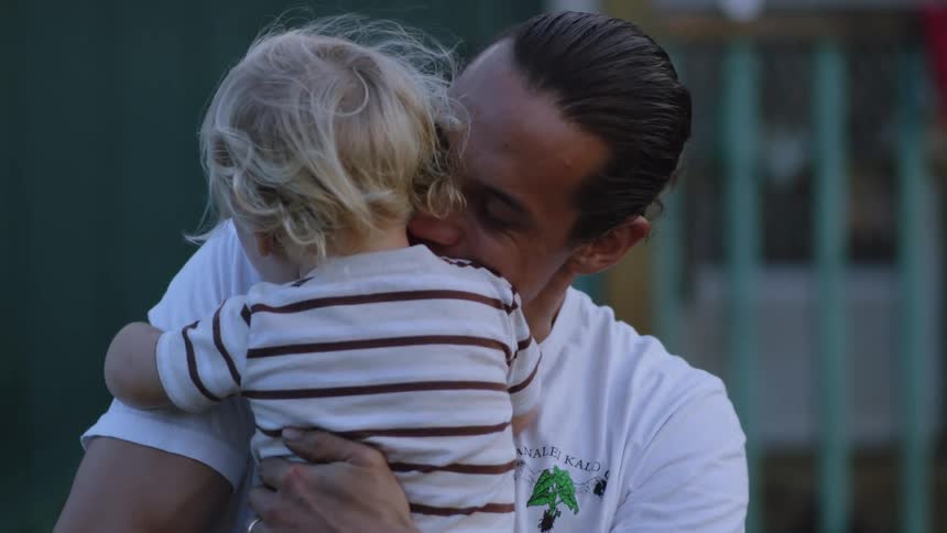 A father is hugging his son outside