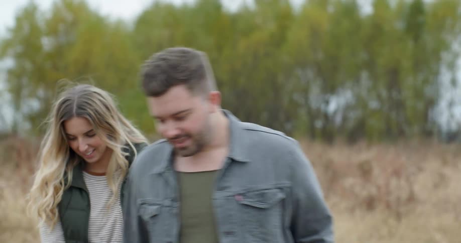 A man and woman walk along a grass field