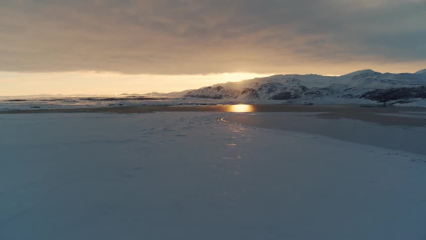 Snowy landscape composed of water in the background and mountains