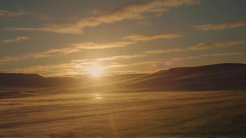 Snowcovered landscape with hills and the sun in the background