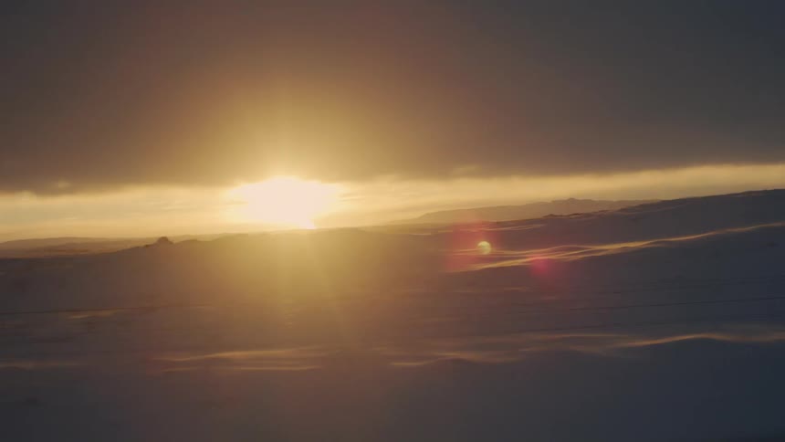 Landscape of a snowy hill with the reflection of the sun on the horizon