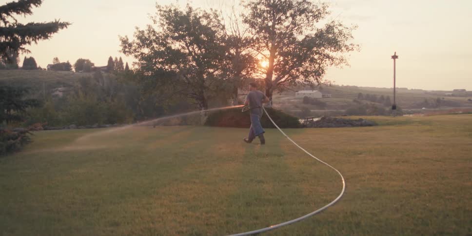 Man with a hose watering the grass in the garden