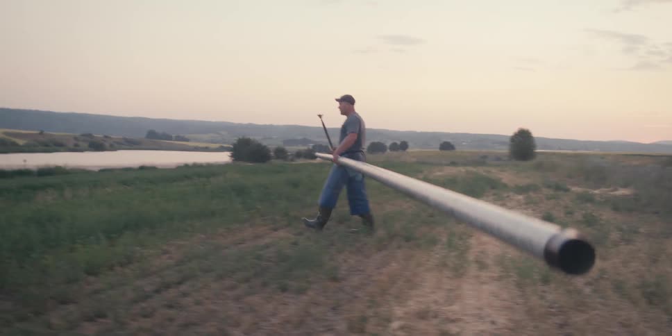 A man walks carrying a long pole