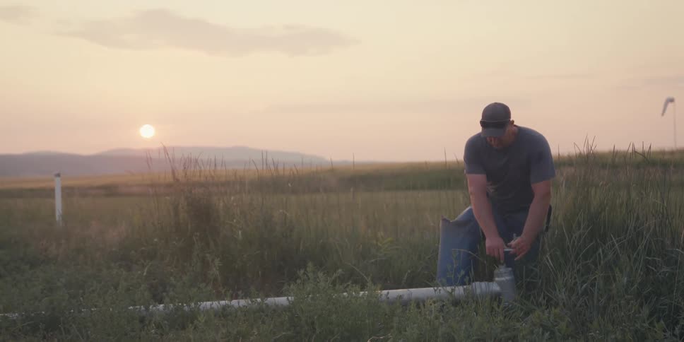 A man holds a pipe in a field
