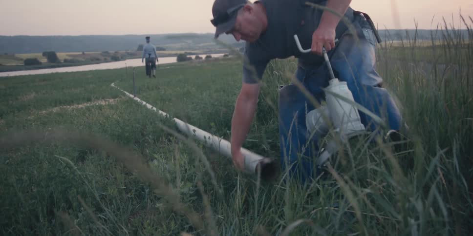 A man attaches a spigot to a long pipe