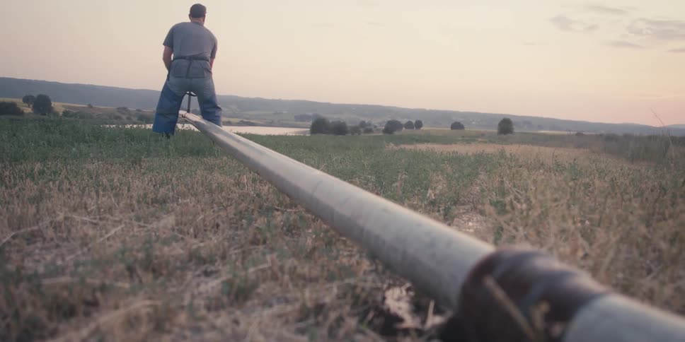 A man attaches a pipe to a water source to irrigate his farm