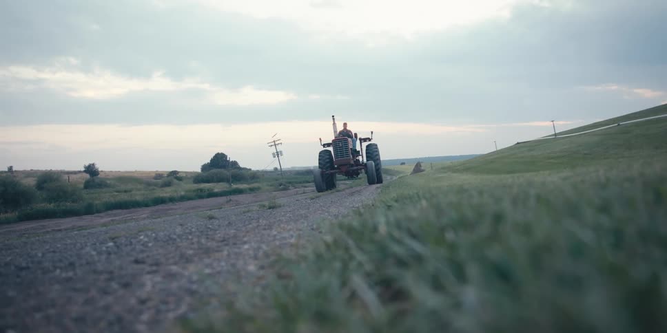 A man drives a tractor down a dirt path