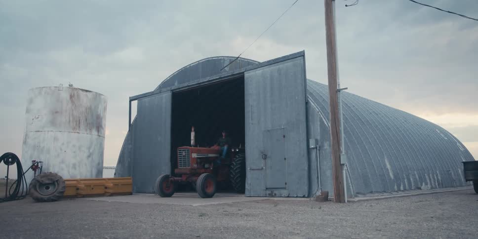 Tractor coming out of an agricultural shed