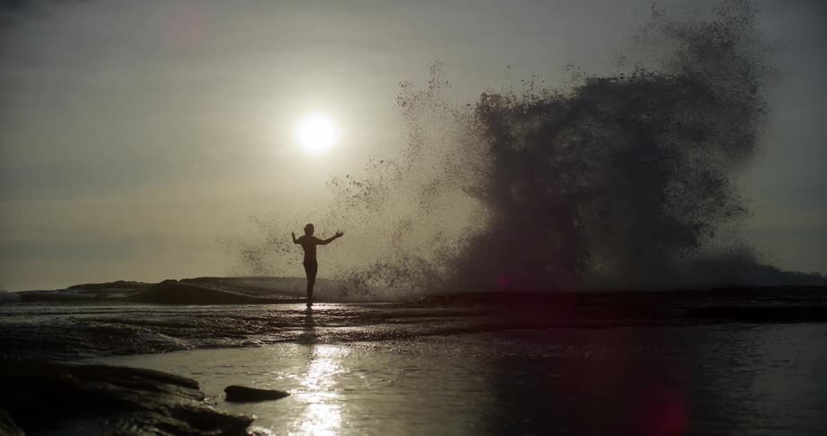 A wave crashes and splashes a person with water