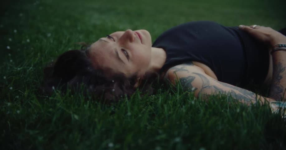 Woman lying on grass with snow falling