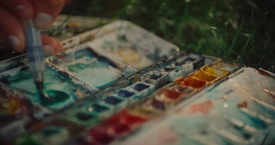 Close up of a womans hand pissing paint onto a piece of paper