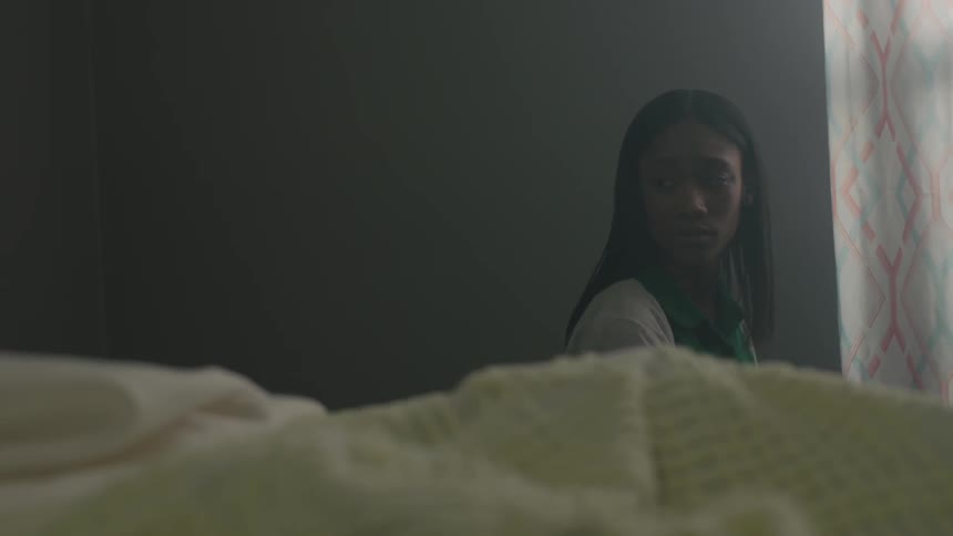 A woman sits straight looking back to a woman in bed