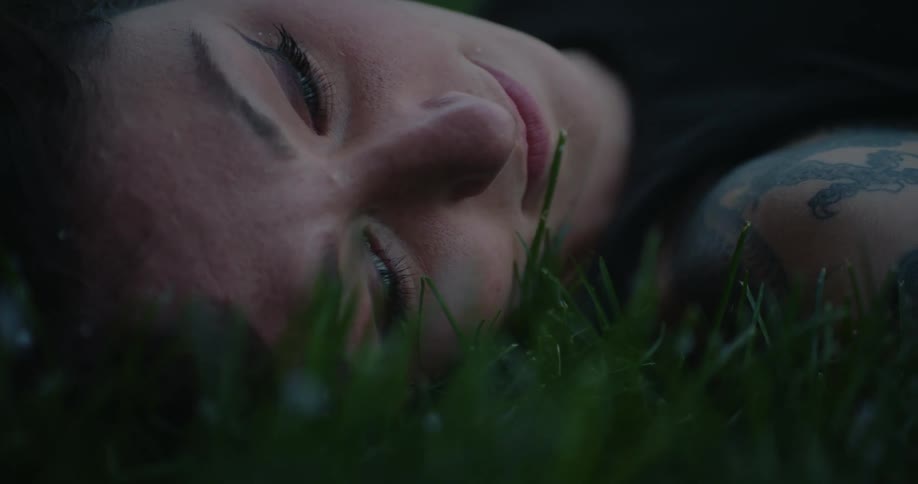 Portrait of a woman lying on grass with snow falling
