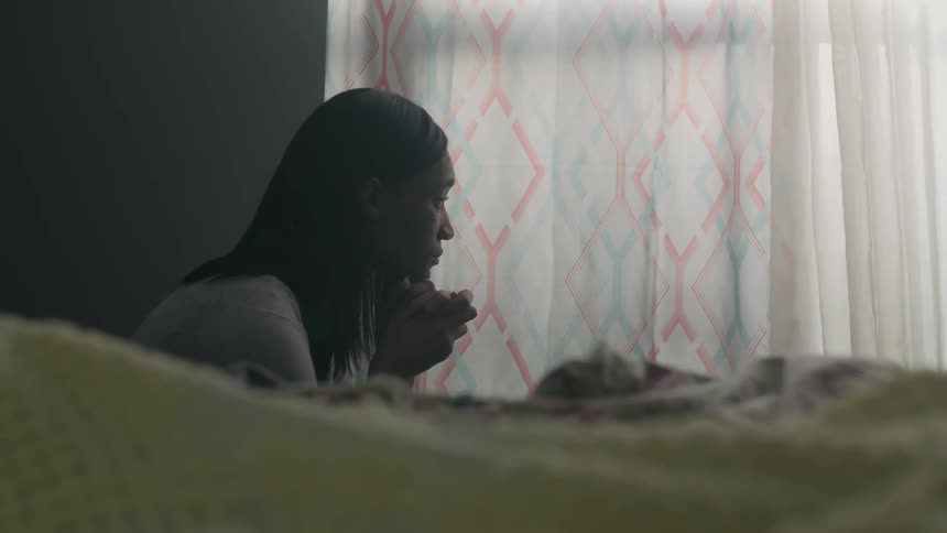 A woman prays by the window