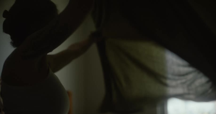 Woman arranging a sheet on a bed in the bedroom