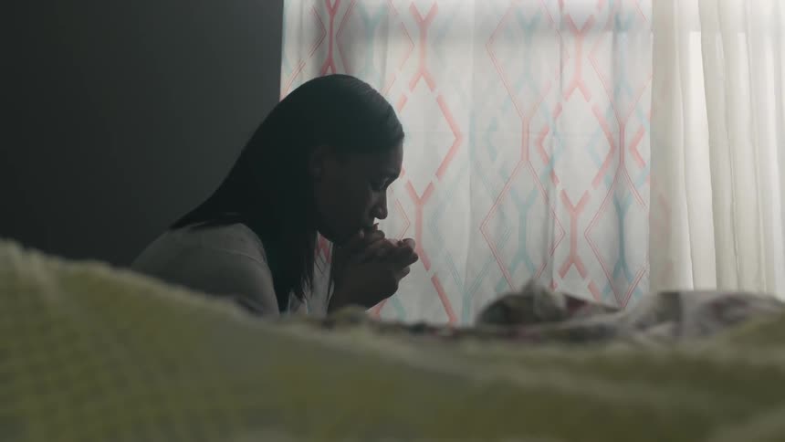 A woman is praying at a window