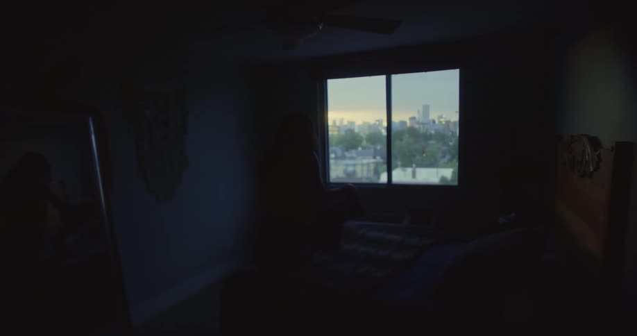 Silhouette of a woman looking at clothes in a room