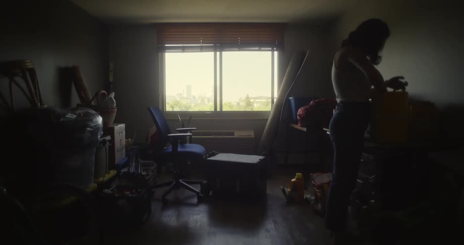 Woman in a room with furniture and boxes taking out objects