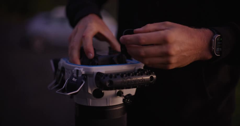 Pair of hands placing a professional camera on a protective stand