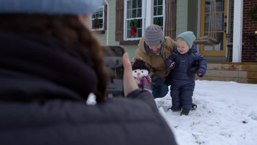 A clip of a father and son posing with a snowman