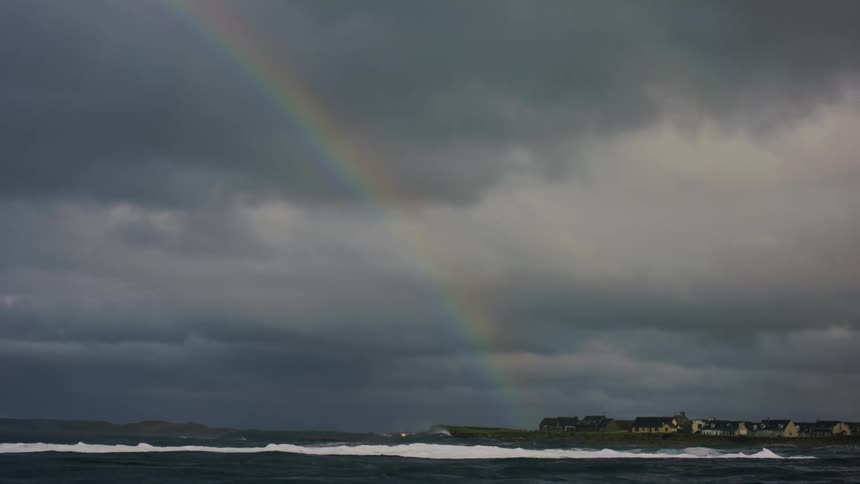 Ocean with moving waters and a rainbow in the background