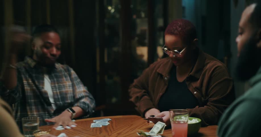 Friends sitting playing cards at a table at night