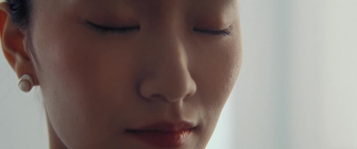 Close up of the face of a woman with her eyes closed in a white room