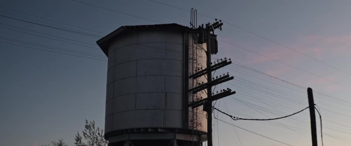 Water tower standing near power lines towers over nearby buildings