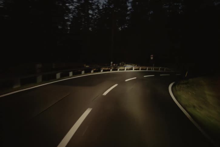 Moving view of a highway at night surrounded by dense forest