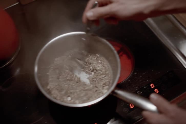 Pair of hands cooking oatmeal on stove