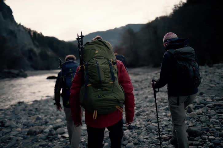 Group of friends hiking across rocks towards a river in a canyon