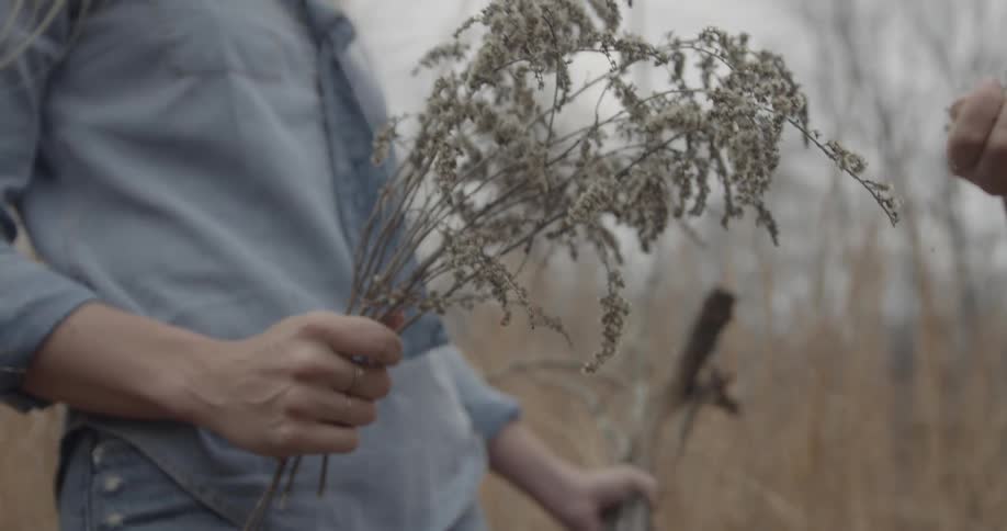A woman carries plants and flowers she picked