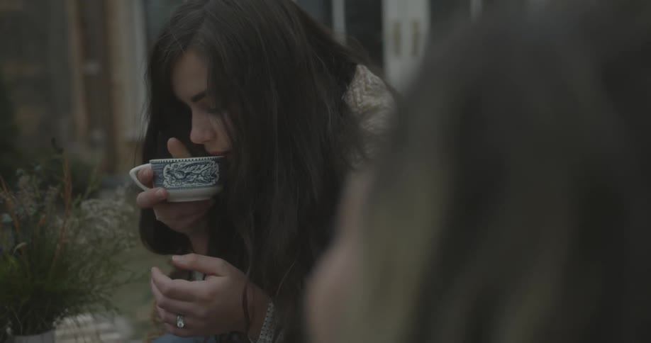 A woman takes a drink from a mug outside