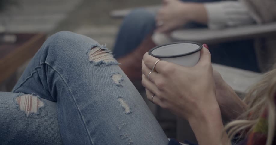 People are sitting down outside with mugs