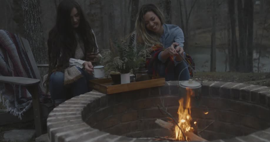 Two women sitting near a fire pit