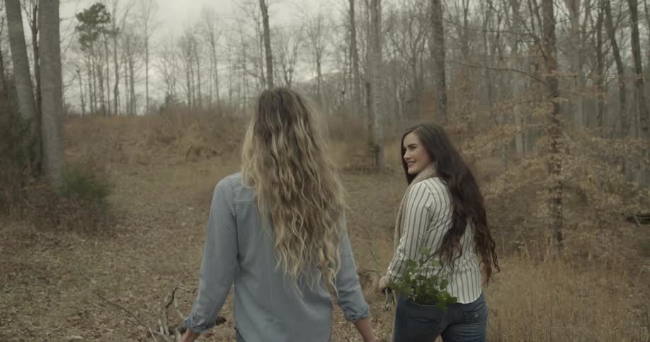Women walk down a path carrying sticks