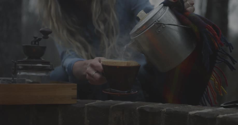 Woman pours steaming water into a mug