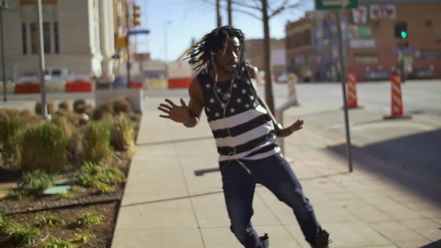 A man in a flag shirt dances on the sidewalk
