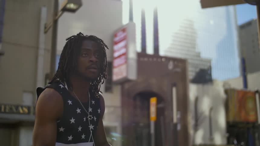 Man with dreadlocks spinning and gesturing on a city street