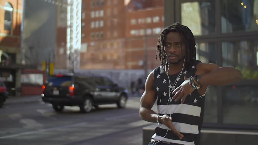 A man wearing earbuds dances on the sidewalk