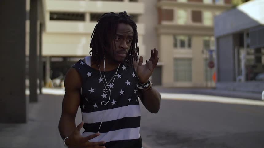 Man with dreadlocks spinning and gesturing on a city street