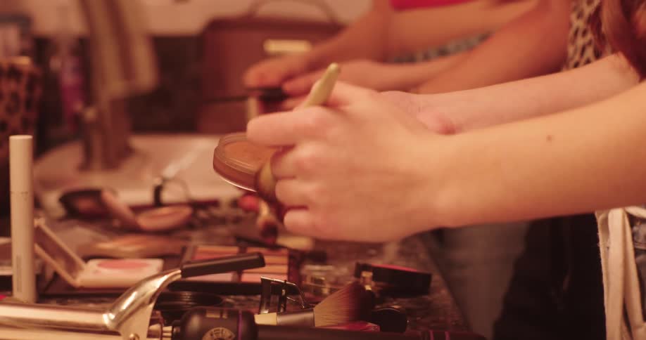 Pair of hands of two women applying makeup with makeup products