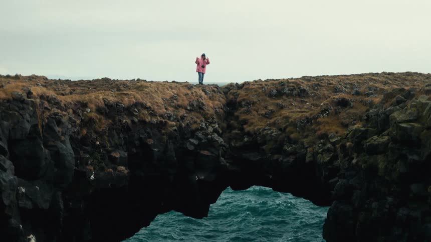 Person walking on a rock above the sea