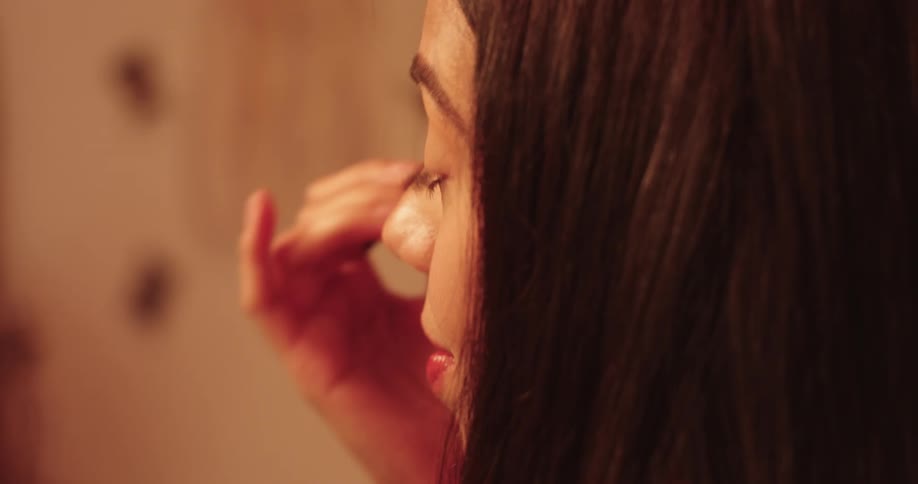 A teenage girl with long hair applying makeup in the bathroom at home