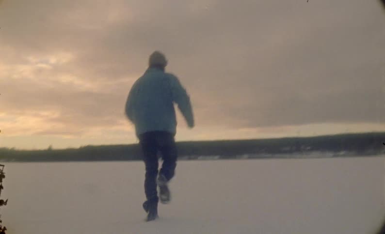 A man is running on a field of snow or a frozen lake at evening