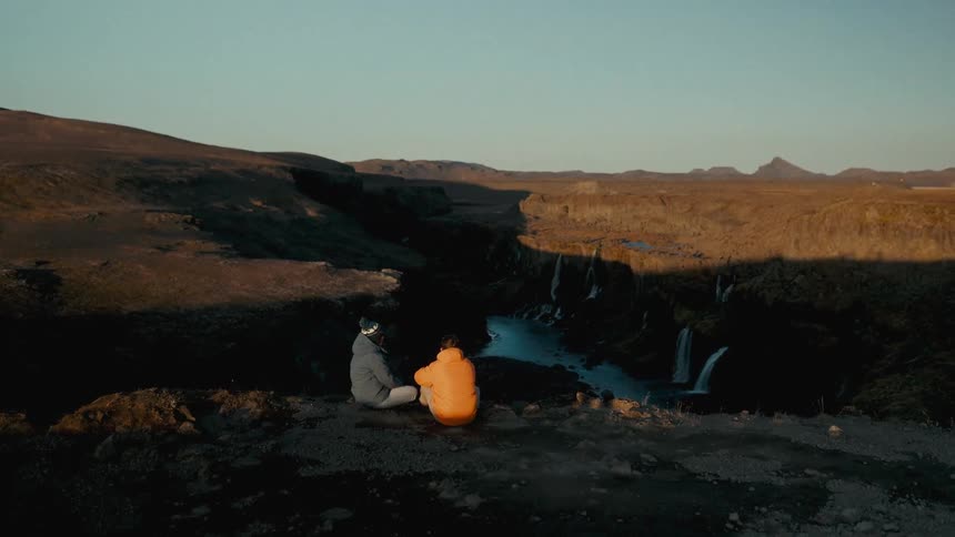 Two people sitting on a mountain cliff