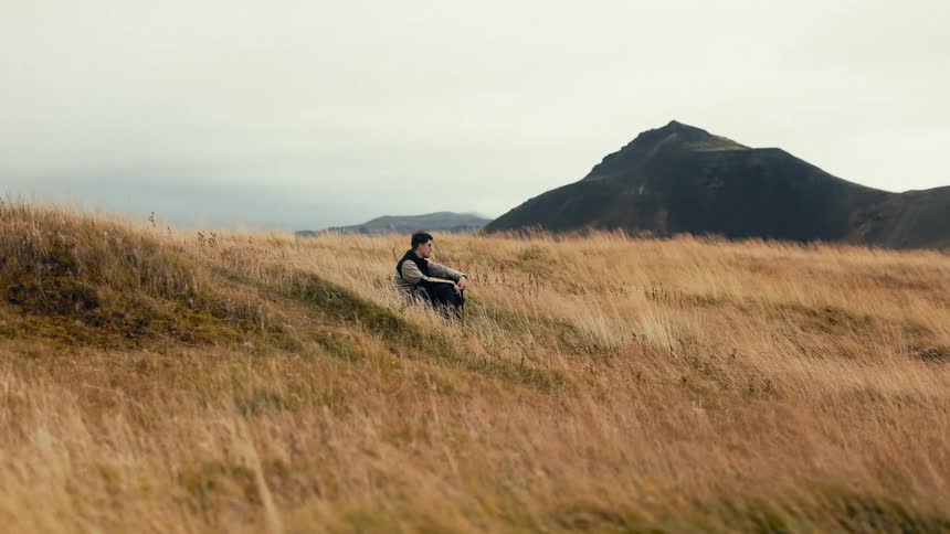 Man sitting on a mountain with reed