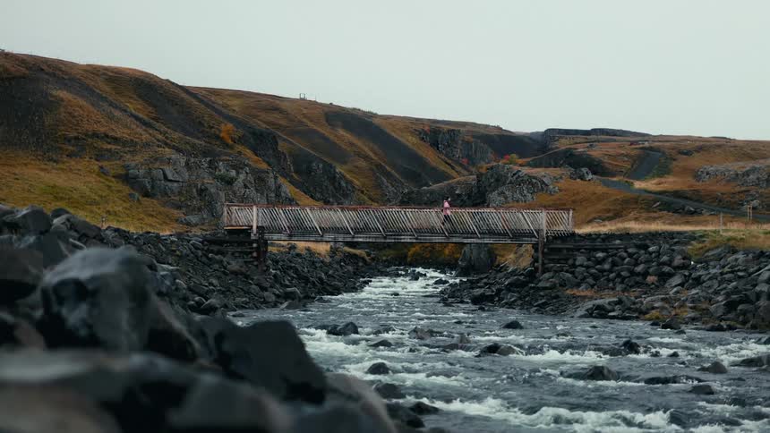 Person crossing a bridge over a river