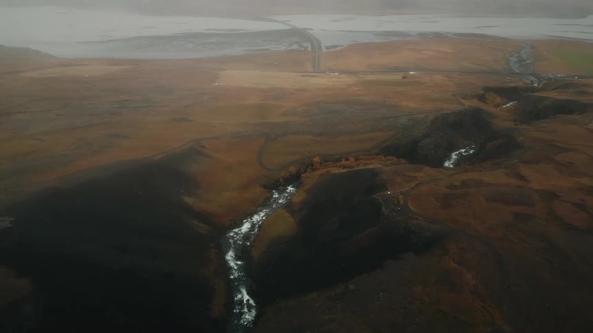 A stream runs through a foggy landscape