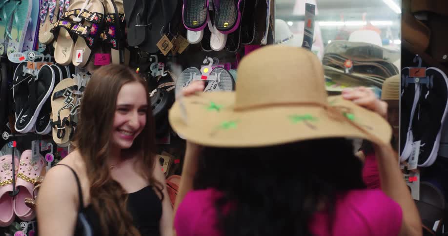 Teenage girls are having fun trying on hats in a store